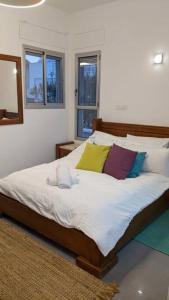ein Schlafzimmer mit einem großen Bett mit bunten Kissen in der Unterkunft סוויטה הילה במצובה in Maẕẕuva