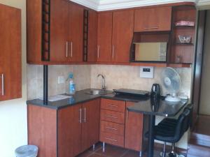 a small kitchen with wooden cabinets and a sink at Genie's Nest 4 in Pretoria