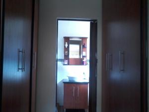 ein Badezimmer mit einem Waschbecken und einem Spiegel zwischen zwei Türen in der Unterkunft Genie's Nest 4 in Pretoria