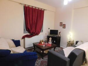 een woonkamer met 2 banken en een rood gordijn bij HOME SWEET HOME in Ioannina