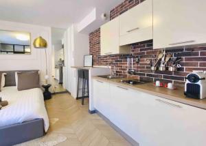 a kitchen with white cabinets and a brick wall at Beautiful Fully Renovated Centrally Located Studio in Monte Carlo
