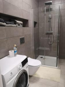 a bathroom with a washing machine and a toilet at Nowoczesny apartament na Promenadach Wroclawskich in Wrocław