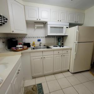 a kitchen with white cabinets and a sink and a refrigerator at Stay ON the beach! Wonderful location! in Daytona Beach