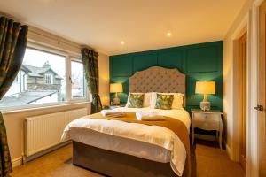 a bedroom with a bed with a green headboard and a window at Holly Lodge Guest House with FREE off site health club in Windermere