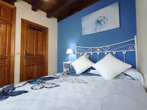 1 dormitorio con 1 cama con pared azul en Del Abuelo Casa Rural, en Prádena del Rincón