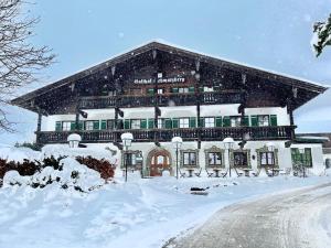 un gran edificio cubierto de nieve delante en Landgasthof Schwarzberg en Inzell