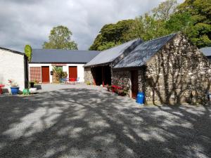 um edifício de pedra com um telhado preto em James Tymon Self-Catering Cottage em Gorteen