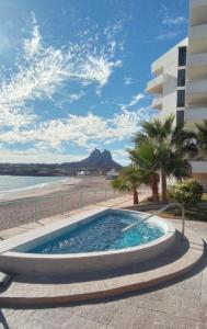 a swimming pool next to a beach and a building at Condominio Posada 314 San Carlos in San Carlos