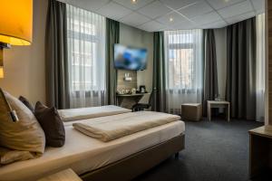 
a hotel room with a bed, chair, and nightstand at Hotel Hohenstaufen in Koblenz
