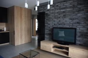 uma sala de estar com televisão e uma parede de tijolos em Uroczy apartament z widokiem i darmowym parkingiem em Poznań