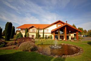 une grande maison avec un étang en face de celle-ci dans l'établissement Tamar Valley Resort Grindelwald, à Grindelwald