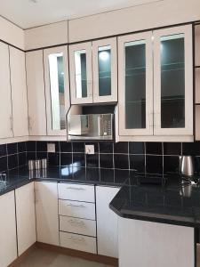 eine Küche mit weißen Schränken und einer schwarzen Arbeitsplatte in der Unterkunft Genie's Nest Ooie 2 in Pretoria