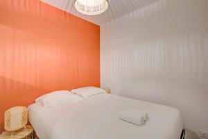 a white bed in a room with an orange wall at Le Langeais Cocoon in the heart of Les Halles in Tours