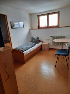a bedroom with a bed and a table and a desk at Ferienwohnung Schwäbische Alb in Justingen