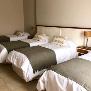 a group of three beds in a hotel room at Green Sea Apart Hotel in Pinamar