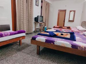 a room with two beds and a tv in it at Vidya Guest House in Katra