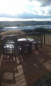 a table and benches on a deck with a view of a river at SHALOM - IN THE HEART OF THE LAKES in Arvagh