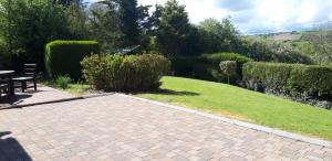 a brick walkway with a table and bench in a garden at SHALOM - IN THE HEART OF THE LAKES in Arvagh