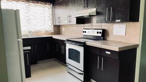 a kitchen with black cabinets and a white stove top oven at Private Rooms in a 3 Bedroom Guest House Close to Kingsway NAIT 1 Person per Room No Couples For Men Only in Edmonton
