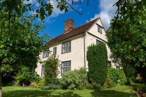 an old house with a hedge in front of it at Pounce Hall -Stunning historic home in rural Essex in Saffron Walden