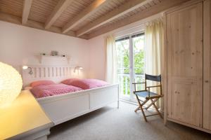 a bedroom with a bed with pink pillows and a window at Pippi´s Ostseetraum in Sierksdorf