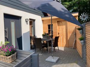 un patio con una mesa con sillas y una sombrilla en Ferienwohnung Am Holzfeld, en Schneverdingen
