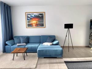ein Wohnzimmer mit einem blauen Sofa und einem Tisch in der Unterkunft Fewo unweit Warnemünde Sobierajczyk in Markgrafenheide in Rostock
