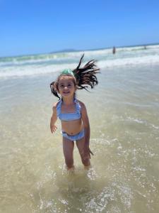 una niñita parada en el agua en la playa en Conchas de Palmas en Governador Celso Ramos