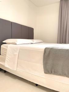 Elle comprend un grand lit avec des draps et des oreillers blancs. dans l'établissement Conchas de Palmas, à Governador Celso Ramos