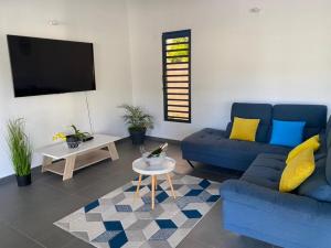 een woonkamer met twee blauwe banken en een tv bij Caribbean’ZEN in Petit-Bourg