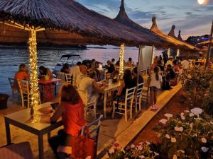 a group of people sitting at tables in a restaurant by the water at Apartment Lola in Srima