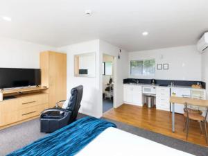 a bedroom with a bed and a table and a kitchen at Drovers Motor Inn in Palmerston North
