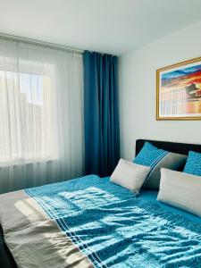 Schlafzimmer mit einem Bett mit blauer Bettwäsche und einem Fenster in der Unterkunft Fewo unweit Warnemünde Sobierajczyk in Markgrafenheide in Rostock