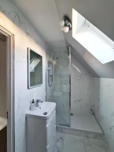 a white bathroom with a shower and a sink at The Corner Cottage in Sandwick