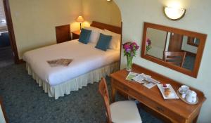 een hotelkamer met een bed en een bureau met een spiegel bij The Ayrshire and Galloway in Ayr