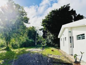 a dirt road next to a white building at A&J Cottage in Le Morne Rouge