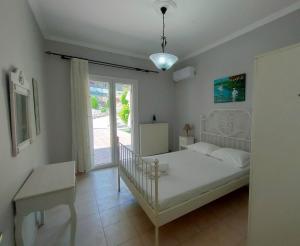 a bedroom with a white bed and a window at Villa Southern Comfort in Lefkímmi +39 photos