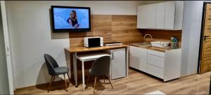 a kitchen with a table and chairs and a tv on the wall at Apartamenty Widokowe Na Szczycie in Korbielów +18 photos