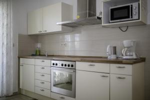 a kitchen with white cabinets and a stove and a microwave at Apartment in Lopar with Terrace, Air conditioning, Wi-Fi (4612-3) in Lopar +18 photos