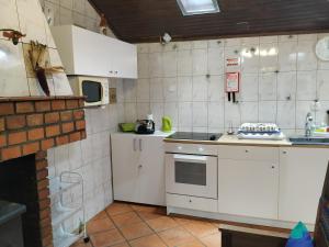 a small kitchen with white cabinets and a stove at Pé na Aldeia in Outeiro