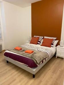 a bed with orange pillows on it in a room at Grand F3 de 71m2 en plein centre ville Arpajon in Arpajon