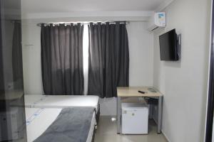 a room with two beds and a desk and a window at Hotel Flor Paulista in São Paulo