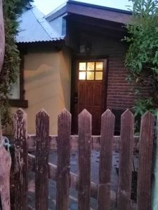 a wooden fence in front of a house with a door at Las Adelas Chaltén in El Chalten