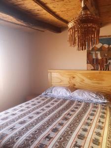 a bedroom with a wooden bed with a chandelier at Hostal Candelaria in San Pedro de Atacama