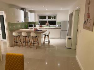 a kitchen with white cabinets and bar stools at Swn yr Coed in Brecon