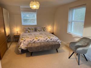 a bedroom with a bed and a chair and two windows at Swn yr Coed in Brecon