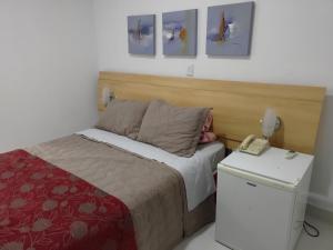 ein kleines Schlafzimmer mit einem Bett und einem Telefon in der Unterkunft Flat na Praia de Camburi, Veja as opções de Quarto in Vitória