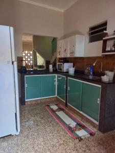 a kitchen with green cabinets and a white refrigerator at Casa milagres in São Miguel dos Milagres