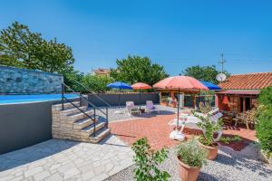 een huis met een zwembad en een patio met parasols bij Apartment with pool Visnjan in Višnjan