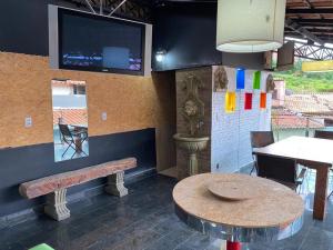 ein Restaurant mit einem Tisch und einem TV an der Wand in der Unterkunft Pousada & Hostel Belo Vale in Santa Luzia